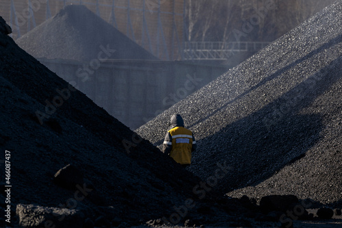 Coal terminal. A man walks among the large coal heaps.