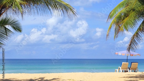 Beach with palm trees and umbrellas to sit and relax on a sunny day at Karon Beach, Phuket, Thailand.