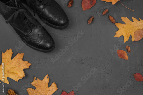 New autumn collection. Preparing for the cold. Boots with autumn leaves on black stone background. Cleaning shoes.
