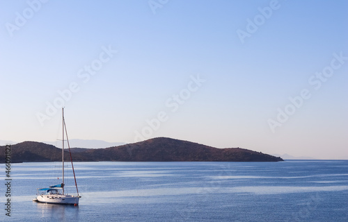 Blue sea, a boat and mountains in sunrise. Tranquil seascape and coastal nature concept