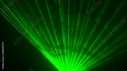 Dynamic green beams of laser neon light on black studio background spinning in puffs of smoke. Show of stage holograms. Lighting equipment and effects for holidays and parties. Close up. photo