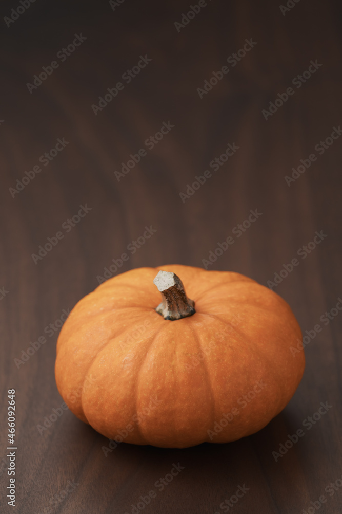 Small orange pumpkin on black walnut table with copy space Small orange pumpkin on black walnut table with copy space