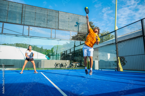 Mixed padel match in a blue grass padel court - .Beautiful girl and handsome man playing padel outdoor