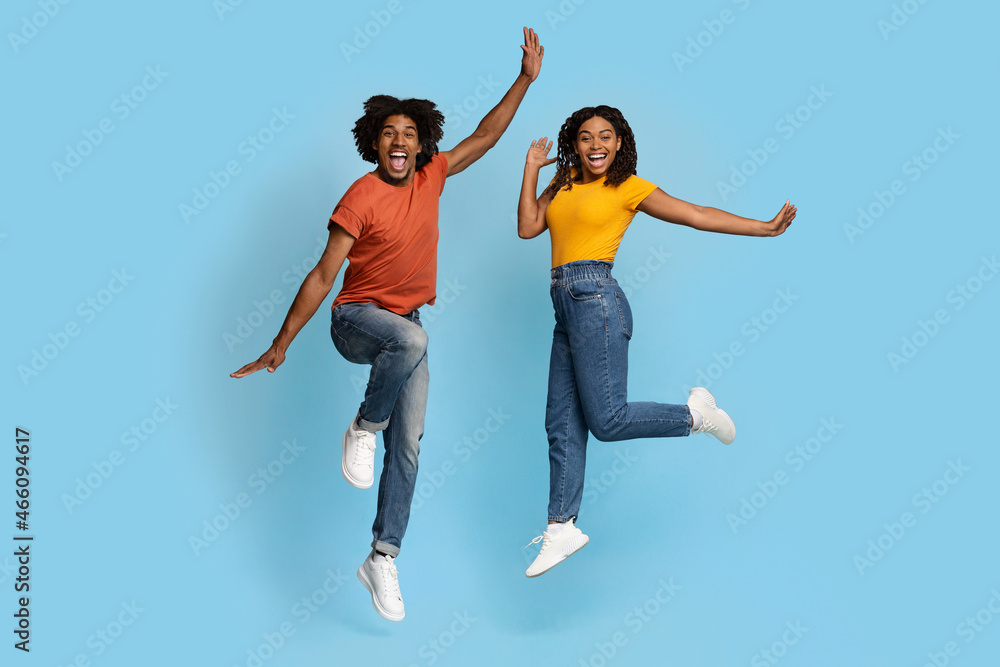 Happy african american lovers jumping over blue studio background Happy african american lovers jumping over blue studio background