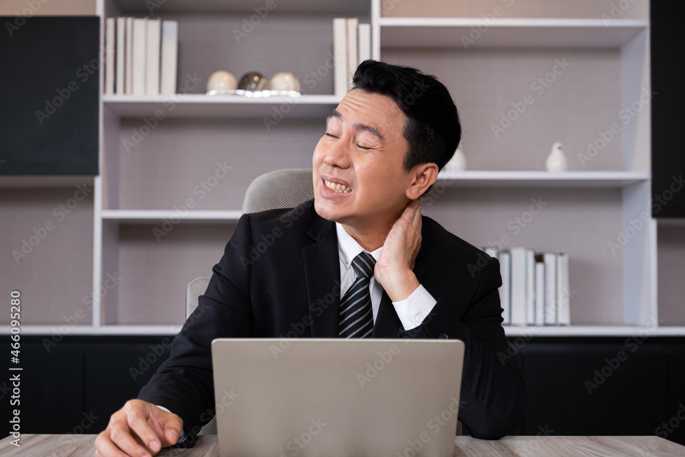 Adult men business person feeling painful from neck and shoulder while working, online meeting in front of the computer inside of the office area. Office syndrome, over working illness. Adult men business person feeling painful from neck and shoulder while working, online meeting in front of the computer inside of the office area. Office syndrome, over working illness.