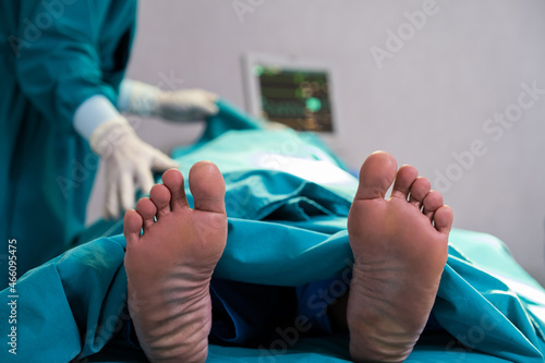 Selective focus at feet of pass away patient while doctor covering face inside of the surgery operation room in the hospital. Illness and death concept.