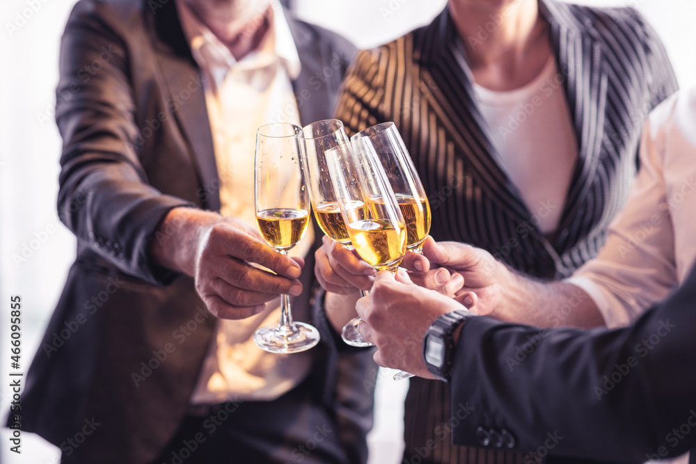 Four business partner celebrating their victory. Old business man making a toss to younger business man and woman. They are holding a champagne glass in a hotel lobby with city scape background. Four business partner celebrating their victory. Old business man making a toss to younger business man and woman. They are holding a champagne glass in a hotel lobby with city scape background.