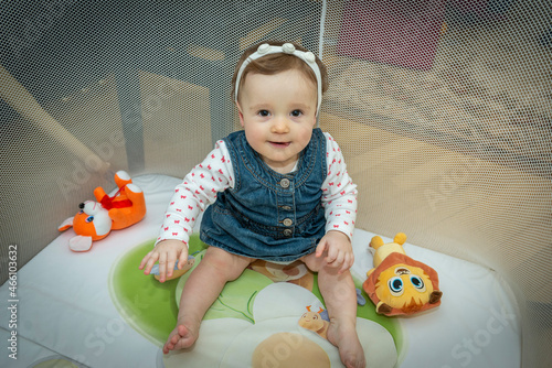 a little baby girl is sitting in an aviary with toys