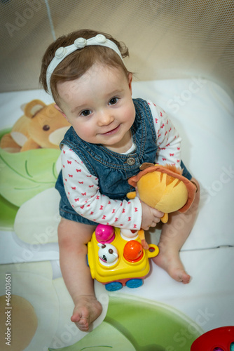 a little baby girl is sitting in an aviary with toys