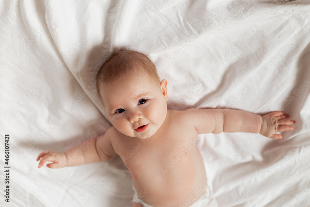 newborn baby in a diaper is lying on his back on a white sheet. products for children, toy. concept of a happy childhood and motherhood. child care. space for text. High quality photo newborn baby in a diaper is lying on his back on a white sheet. products for children, toy. concept of a happy childhood and motherhood. child care. space for text. High quality photo