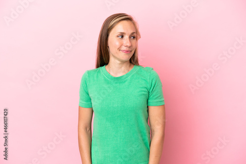 Young English woman isolated on pink background having doubts while looking side