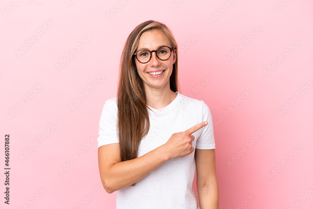 Young English woman isolated on pink background pointing to the side to present a product Young English woman isolated on pink background pointing to the side to present a product