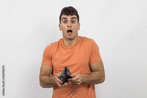 a young boy showing his wallet because he has no money on a white background.