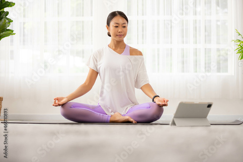 Morning yoga with an Asian woman, sitting in Easy position, Sukhasana posture, and meditating online.
