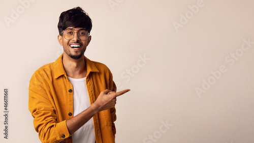 Positive young indian man pointing at copy space photo