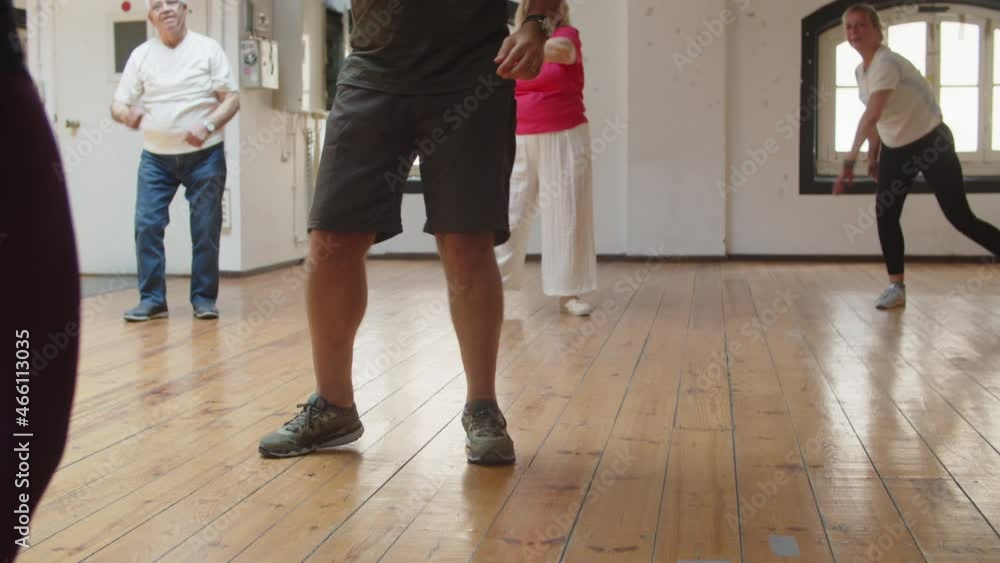 Senior people having dance class with teacher in ballroom. Close-up shot of dancers legs in sneakers moving and stepping side to side on floor. Community, hobby, retirement concept Senior people having dance class with teacher in ballroom. Close-up shot of dancers legs in sneakers moving and stepping side to side on floor. Community, hobby, retirement concept