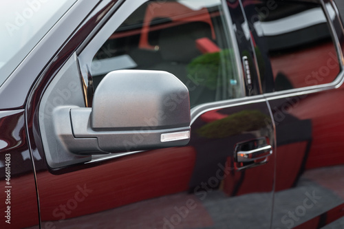 Close-up of the side left mirror and window of the car body black SUV on the street parking after washing. Road safety while driving. Exterior detail