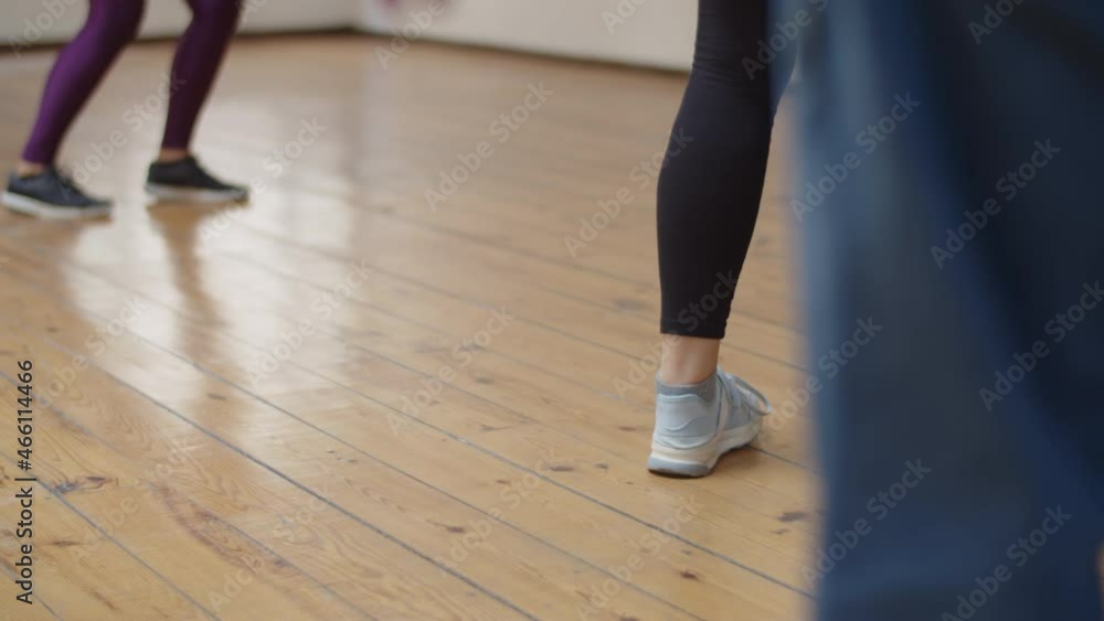 Close-up shot of womans feet dancing in ballroom. Back view of female person wearing sneakers having dance class with instructor, learning movements, exercising together. Dance class, sport concept Close-up shot of womans feet dancing in ballroom. Back view of female person wearing sneakers having dance class with instructor, learning movements, exercising together. Dance class, sport concept