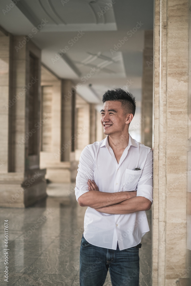 Portrait of asian young handsome man in casual clothing standing outdoors and smiling. Chinese people, real life, looking at camera with copy space Portrait of asian young handsome man in casual clothing standing outdoors and smiling. Chinese people, real life, looking at camera with copy space