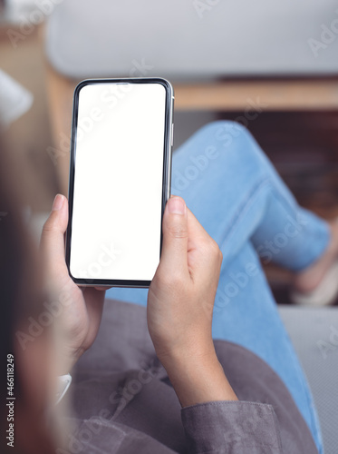 Cell phone mockup image blank white screen.  Woman hand holding, using mobile phone at home.