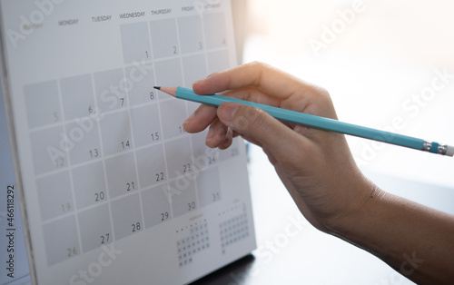 Close-up of business woman taking note on calendar desk, making agenda on office table. Event planner timetable. Calendar event plan