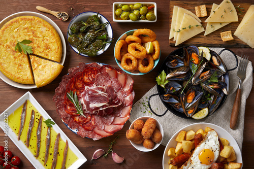 A wooden table with typical Spanish food seen from above