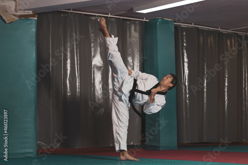 40-year-old Korean kicking taekwondo on a tatami mat. photo