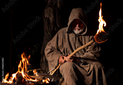Photography Old medieval monk by the fire with torch