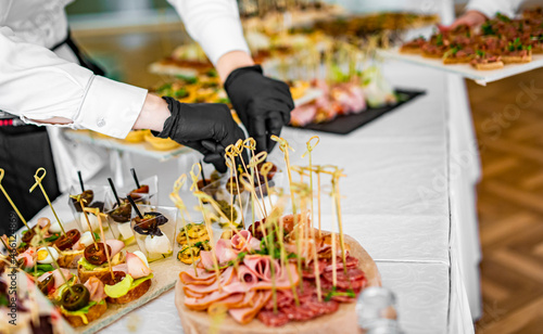 Fototapeta Naklejka Na Ścianę i Meble -  woman hands of a waiter prepare food for a buffet table in a restaurant