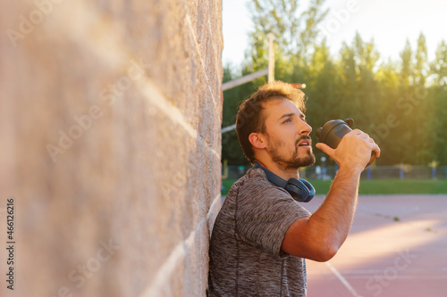 фотографія Male athlete drinking or taking his dose of whey protein, bcaa, creatine, casein or energy drink, after a hard workout outside at sunset