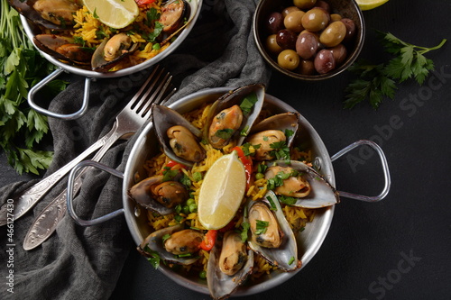 Traditional spanish seafood paella in the fry pan. Spanish paella with clamps, mussels, and fresh lemon wedges