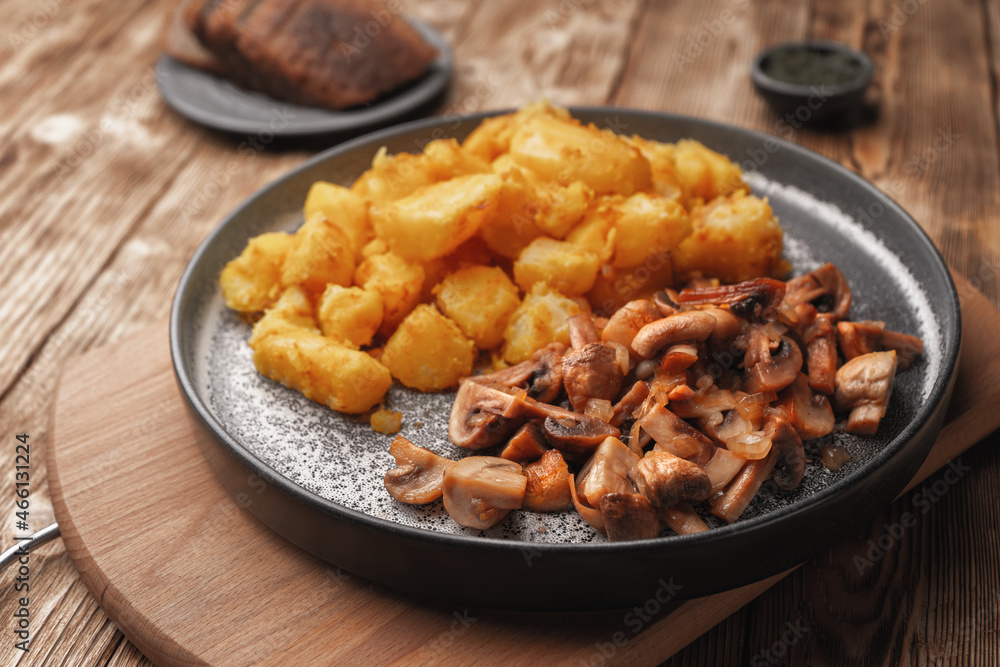 Fried potatoes with mushrooms on a concrete plate. Fried potatoes with mushrooms on a concrete plate.