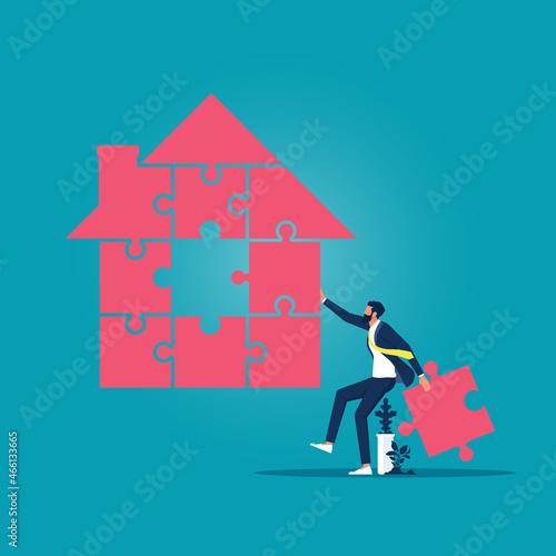 Businessman holding jigsaw pieces to finish a house shape puzzle, solving home mortgage problems concept