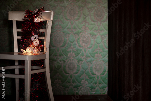 Winter. Christmas decoration on a rustic chair. Christmas ornament, red - gold color, with shining lamps.