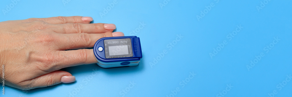 Senior Woman Using Pulse Oximeter, Measuring Oxygen Saturation. Human hand pulse oximeter used to measure pulse rate and oxygen levels with medical blue background with copy space Senior Woman Using Pulse Oximeter, Measuring Oxygen Saturation. Human hand pulse oximeter used to measure pulse rate and oxygen levels with medical blue background with copy space