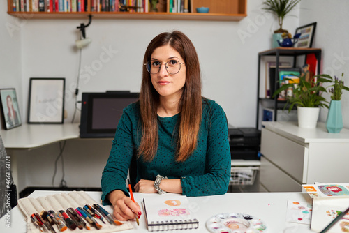 Portrait of a female illustrator looking at camera in her artist studio