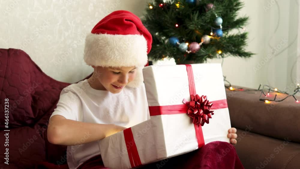 Close-up shot of Happy adorable boy opening his Christmas present. Cozy Christmas interior. Winter holidays Close-up shot of Happy adorable boy opening his Christmas present. Cozy Christmas interior. Winter holidays