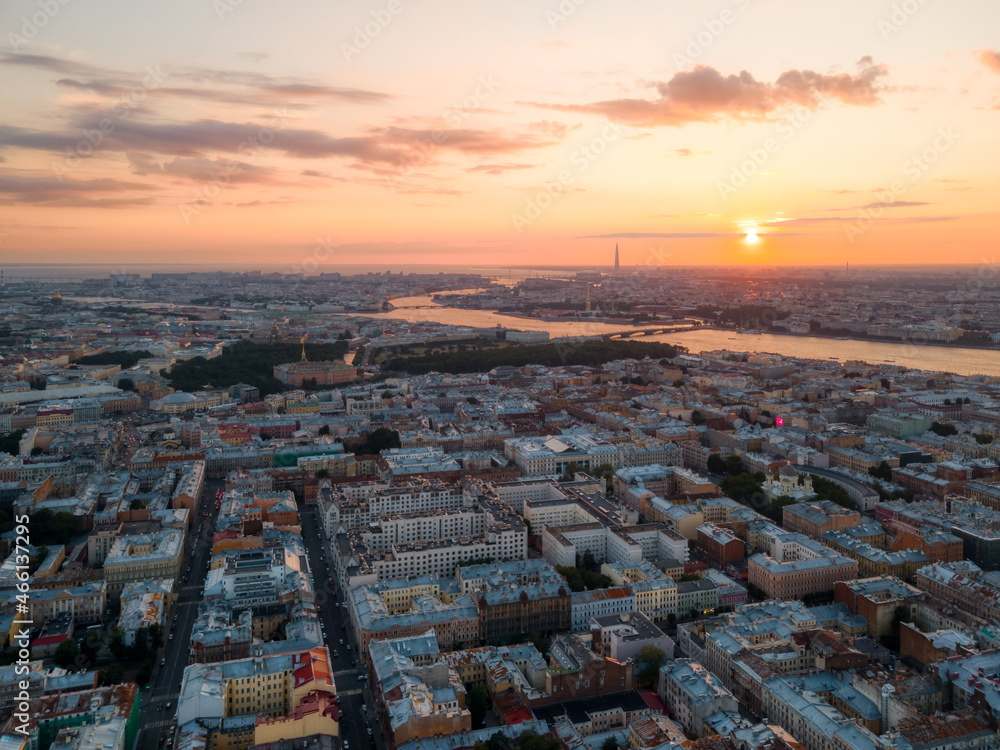 Cloudy orange sunset above Saint Petersburg, Russia. Aerial photo from drone. Old residential houses and Neva river on the ground. Skyscraper on background. Wanderlust concept.