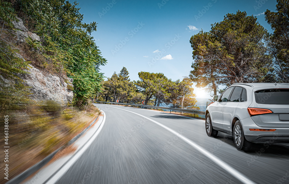 White car on a scenic road. Car on the road surrounded by a magnificent natural landscape.