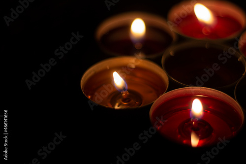 Candle flames in the dark. Candles burn with yellow fire. Liquid wax gradually melts.