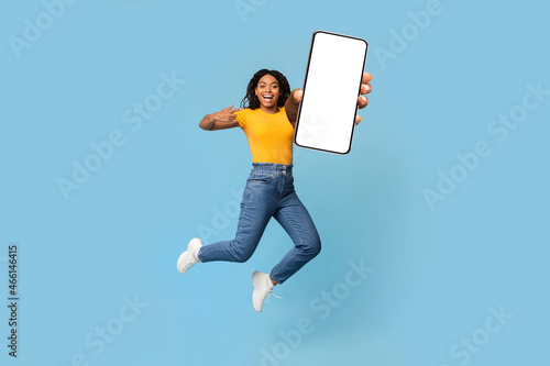 Positive african american woman showing big smartphone with blank screen