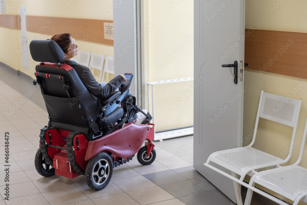 Caucasian woman in electric wheelchair in university corridor. Caucasian woman in electric wheelchair in university corridor.