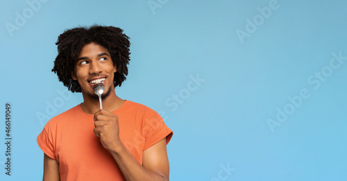 Curious african american man with spoon in his mouth