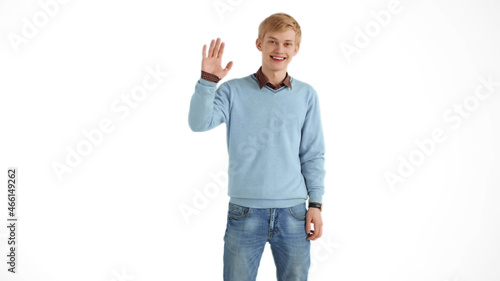 Portrait of friendly smiling man waving raised hand saying hello and looking happy