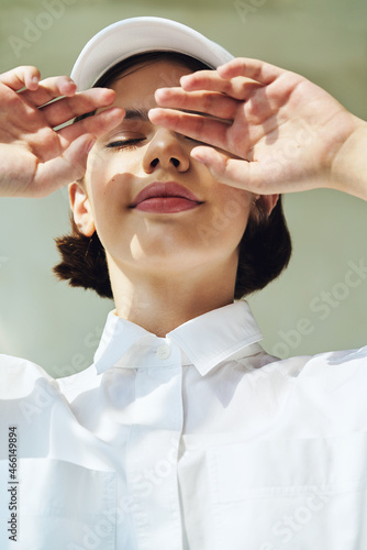 Portrait of sensual young girl in white cap and shirt in sunlight photo