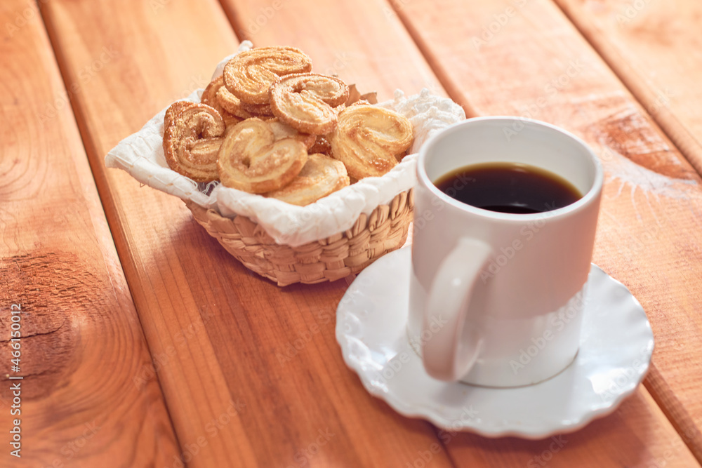 Palm cookies or puff pastry ears and a cup of coffee on a wooden table. Palm cookies or puff pastry ears and a cup of coffee on a wooden table.