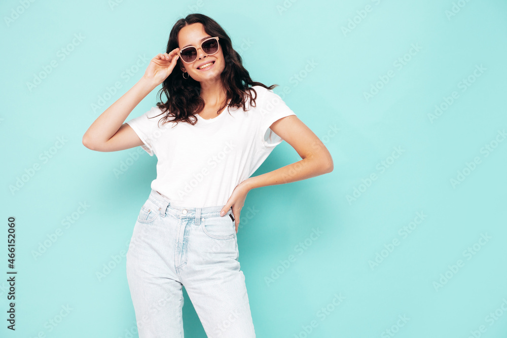 Portrait of young beautiful smiling female in trendy summer clothes. Sexy carefree woman posing near blue wall in studio. Positive model having fun indoors. Cheerful and happy. In sunglasses Portrait of young beautiful smiling female in trendy summer clothes. Sexy carefree woman posing near blue wall in studio. Positive model having fun indoors. Cheerful and happy. In sunglasses