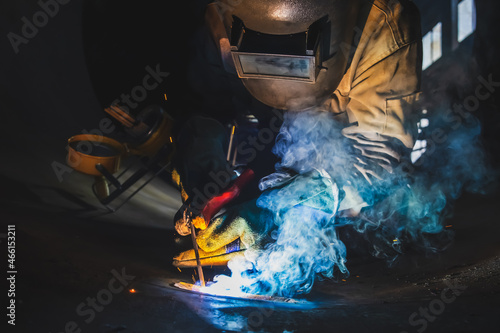 MMA welding. A welder welds large diameter pipes with manual electric arc welding.