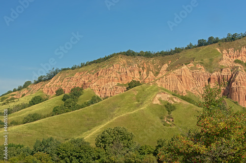 Slopes of Rapa Rosie, the grand canyon of Romania, with orange rocks and green meadows photo