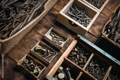 Various screws, nails and old work tools in the container boxes background.